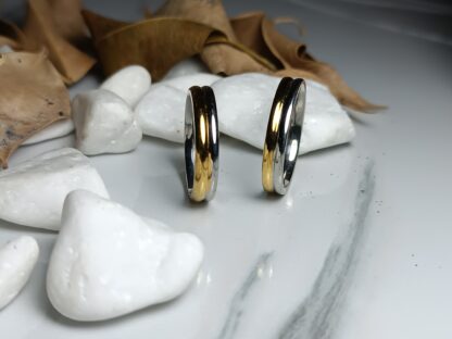 Pair of wedding rings in a combination of silver & gold color on a polished surface (CODE: 50001)
